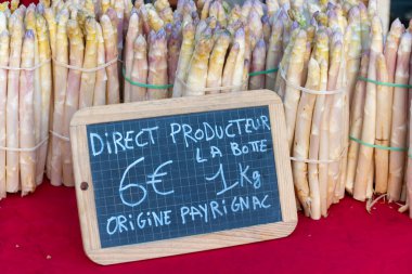 Souillac, Dordogne, Fransa 'daki yerel çiftçi pazarında satılık taze çiğ, pembe kuşkonmaz sebzeleri. İngilizce çeviri: Payrignac 'ta yerel üretilen 1 kg deste