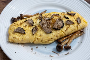 French omelette with mushrooms, fresh farmers chicken eggs and black summer truffle mushroom in pieces for making truffle dishes with tasty aroma clipart