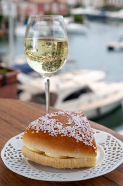 Fransız Rivierası 'nın şarap ve kekleri, bir bardak soğuk beyaz Cote de Provence şarabı ve Port Grimaud limanında Tarte Tropezienne keki, Fransa' nın Provence şehrinde yaz tatili