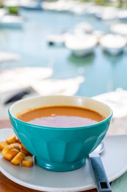 Homemade tasty fish or bisque soup with croutons served outdoor and view on yacht boats and houses of Port Grimaud, French Riviera, France. Food of Provence clipart