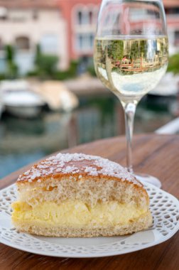 Fransız Rivierası 'nın şarap ve kekleri, bir bardak soğuk beyaz Cote de Provence şarabı ve Port Grimaud limanında Tarte Tropezienne keki, Fransa' nın Provence şehrinde yaz tatili