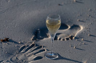 Glass of cava or champagne sparkling wine, winter vacation, low tide on Dunes Corralejo sandy beach, Fuerteventura, Canary islands, Spain clipart