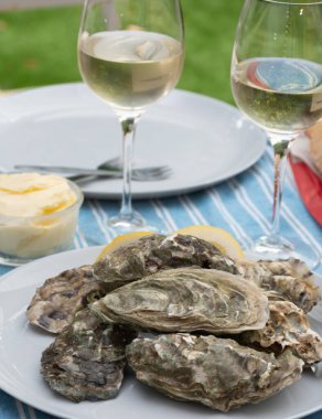 Plate with fresh live raw oysters seashells with citron, bread, butter and white wine served at restaurant in oyster-farming village, Arcachon bay, Gujan-Mestras port, France clipart