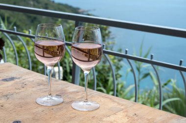 Provence 'de yaz mevsimi, arka planda mavi deniz manzaralı iki bardak soğuk gül şarabı, Fransa' nın güneyinde Menton ve Monako yakınlarında Fransız Rivierası.