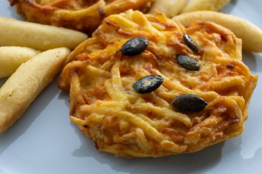 Pumpkin grated roasted patties, rosti or latkes and Fingernudel, finger potato noodle, dumplings decorated with pumpkin seeds close up clipart