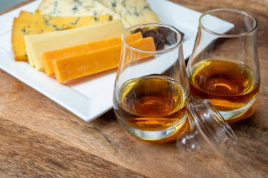Viski ve peynir eşleşmesi, İskoç speyside viski bardakları ve dilimlenmiş çedar, mavi stilton ve mavi shropshire peyniri, İngiltere 'nin yiyecek ve içeceği.