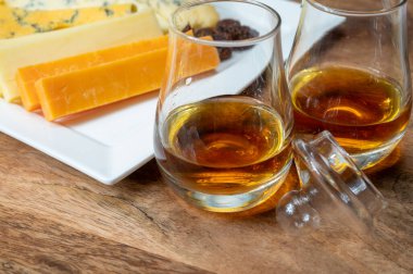 Viski ve peynir eşleşmesi, İskoç speyside viski bardakları ve dilimlenmiş çedar, mavi stilton ve mavi shropshire peyniri, İngiltere 'nin yiyecek ve içeceği.