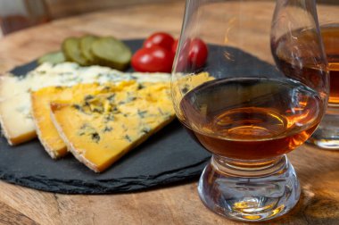 Viski ve peynir eşleşmesi, viski kadehleri ve dilimlenmiş eski mavi stilton ve mavi shropshire peynirleri, İngiltere 'nin yiyecek ve içeceği.