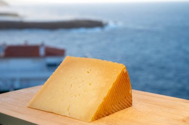 Spanish hard cheese, cow and sheep curado, manchego, goat cheese served outdoor with blue sea on background, close up clipart