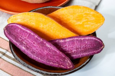 Renkli tatlı tadımlık tüberküloz kökleri mor ve turuncu organik tatlı patatesler, vejetaryen yemekleri, yakın plan.