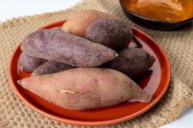 Renkli tatlı tadımlık tüberküloz kökleri mor ve turuncu organik tatlı patatesler, vejetaryen yemekleri, yakın plan.