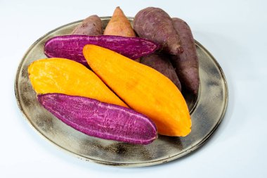 Renkli tatlı tadımlık tüberküloz kökleri mor ve turuncu organik tatlı patatesler, vejetaryen yemekleri, yakın plan.
