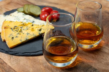 Viski ve peynir eşleşmesi, viski kadehleri ve dilimlenmiş eski mavi stilton ve mavi shropshire peynirleri, İngiltere 'nin yiyecek ve içeceği.