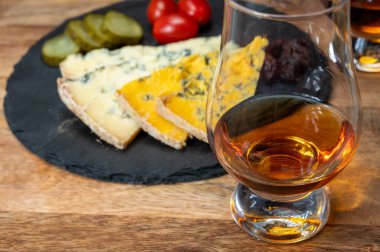 Viski ve peynir eşleşmesi, viski kadehleri ve dilimlenmiş eski mavi stilton ve mavi shropshire peynirleri, İngiltere 'nin yiyecek ve içeceği.