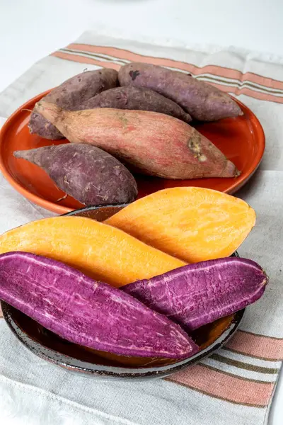 Renkli tatlı tadımlık tüberküloz kökleri mor ve turuncu organik tatlı patatesler, vejetaryen yemekleri, yakın plan.