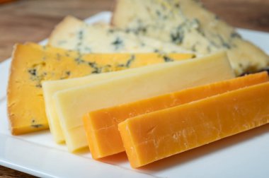 İngiliz peynirli tadım tabağı, İskoç renkli ve İngiliz olgun çedar peyniri, mavi stilton ve sarı shropshire peyniri yakın çekim