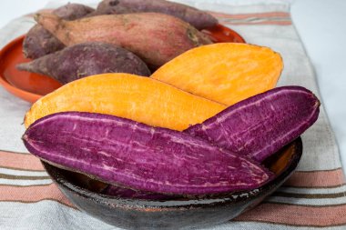 Renkli tatlı tadımlık tüberküloz kökleri mor ve turuncu organik tatlı patatesler, vejetaryen yemekleri, yakın plan.