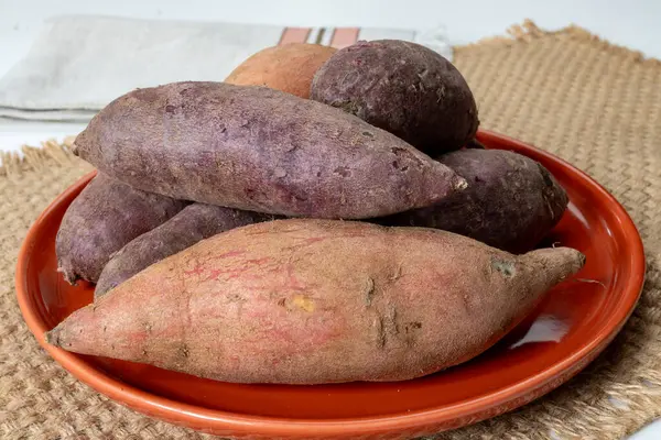 Renkli tatlı tadımlık tüberküloz kökleri mor ve turuncu organik tatlı patatesler, vejetaryen yemekleri, yakın plan.