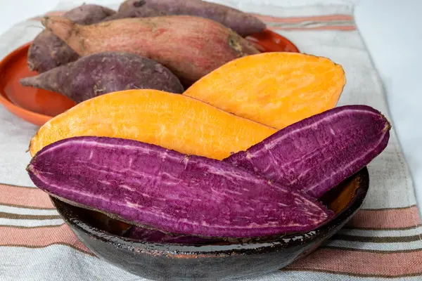 Renkli tatlı tadımlık tüberküloz kökleri mor ve turuncu organik tatlı patatesler, vejetaryen yemekleri, yakın plan.