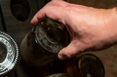 Şampanya şişelerinin elle delik deşik edilmesi geleneksel köpüklü şarap üretimi, şampanya üretimi endüstrisi, Avrupa 'nın bir parçası. İşçinin elleri.