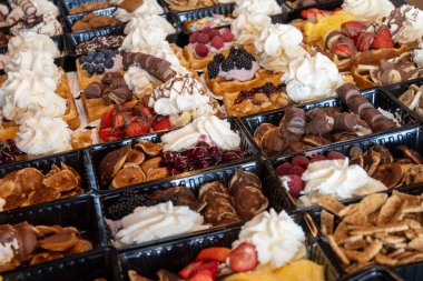 Farklı malzemelerle zenginleştirilmiş taze waffle çeşitleri, tatlı tatlılar, çikolata, krema, meyve ve meyveler, pastanede şekerleme dükkanı, eski Volendam, geleneksel Hollanda tatlıları