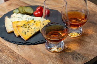 Viski ve peynir eşleşmesi, viski kadehleri ve dilimlenmiş eski mavi stilton ve mavi shropshire peynirleri, İngiltere 'nin yiyecek ve içeceği.