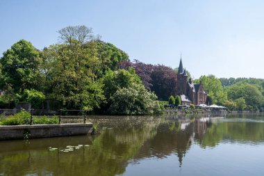Bruges kasabası, Flanders, Belçika 'da güzel eski binaları olan göl ve şehir parkı manzarası.