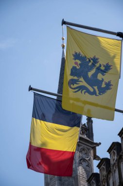 Belçika ulusal bayrağı ve Flanders 'ın sarı bayrağı Bruges, Belçika, mavi gökyüzünde rüzgarda dalgalanıyor