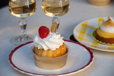 Fransız mutfağı, fırında pişmiş baba romlu kek, kremalı tatlı tatlı, rom ve taze ahududu, ve bir kadeh şampanya şarabı, yakın plan.