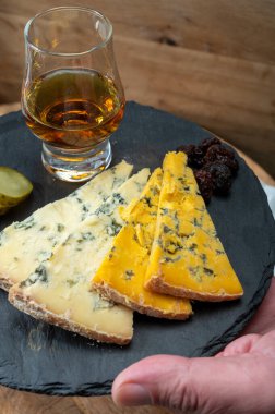 Viski ve peynir eşleşmesi, viski kadehleri ve dilimlenmiş eski mavi stilton ve mavi shropshire peynirleri, İngiltere 'nin yiyecek ve içeceği.