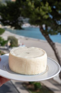 Primo İndirimli Sert Peynir. Karışık sütten yapılmış. Sicilya sepetinin ince kabuğu ve deseni turşulu kapari ve Sicilya, Mondello sahilinde deniz manzaralı.