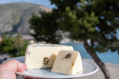 Primo İndirimli Sert Peynir. Karışık sütten yapılmış. Sicilya sepetinin ince kabuğu ve deseni turşulu kapari ve Sicilya, Mondello sahilinde deniz manzaralı.