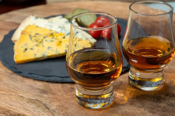 Viski ve peynir eşleşmesi, viski kadehleri ve dilimlenmiş eski mavi stilton ve mavi shropshire peynirleri, İngiltere 'nin yiyecek ve içeceği.