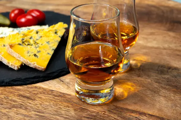 Viski ve peynir eşleşmesi, viski kadehleri ve dilimlenmiş eski mavi stilton ve mavi shropshire peynirleri, İngiltere 'nin yiyecek ve içeceği.