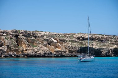 Trapani 'den tekne gezisi ve açık turkuvaz suyu, tuff kayaları, terk edilmiş taş ocakları, Sicilya, İtalya yakınlarındaki Egadi Adaları ile birlikte Favignana adasının kıyı şeridi manzarası.