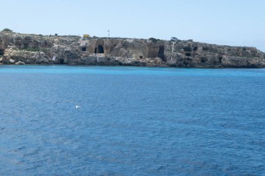 Trapani 'den tekne gezisi ve açık turkuvaz suyu, tuff kayaları, terk edilmiş taş ocakları, Sicilya, İtalya yakınlarındaki Egadi Adaları ile birlikte Favignana adasının kıyı şeridi manzarası.