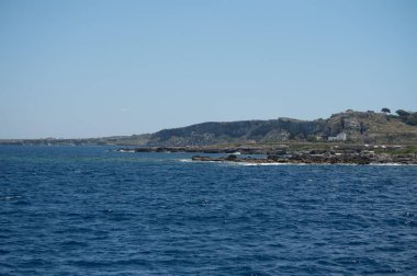 Trapani 'den tekne gezisi ve açık turkuvaz suyu, tuff kayaları, terk edilmiş taş ocakları, Sicilya, İtalya yakınlarındaki Egadi Adaları ile birlikte Favignana adasının kıyı şeridi manzarası.
