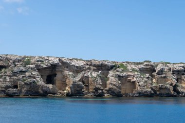 Trapani 'den tekne gezisi ve açık turkuvaz suyu, tuff kayaları, terk edilmiş taş ocakları, Sicilya, İtalya yakınlarındaki Egadi Adaları ile birlikte Favignana adasının kıyı şeridi manzarası.