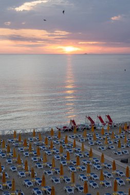 Güneşli yataklarda gün batımı manzarası ve şemsiyeler Mondello Sahili 'nde, Sicilya' da Palermo yakınlarında, güzel, altın kumu, turkuaz suları ve büyüleyici villaları olan popüler sahil kenarı.