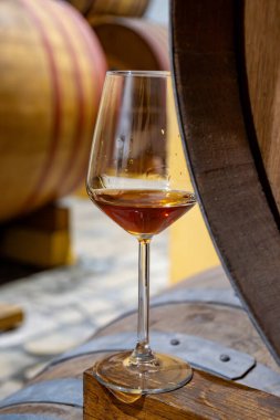 Eski büyük meşe fıçılarıyla şarap mahzenini ziyaret etmek, Marsala, Sicilya, İtalya ve şarap endüstrisindeki varillerden alınmış bir bardak güçlendirilmiş veya lezzetli marsala şarabı.