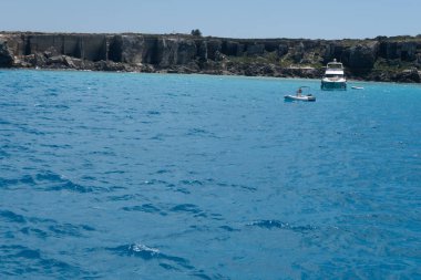 Trapani 'den tekne gezisi ve açık turkuvaz suyu, tuff kayaları, terk edilmiş taş ocakları, Sicilya, İtalya yakınlarındaki Egadi Adaları ile birlikte Favignana adasının kıyı şeridi manzarası.