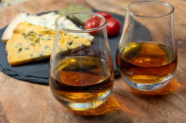 Viski ve peynir eşleşmesi, viski kadehleri ve dilimlenmiş eski mavi stilton ve mavi shropshire peynirleri, İngiltere 'nin yiyecek ve içeceği.