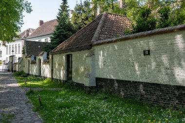 Bruges, Flanders 'da dantel ören rahibeler için ortaçağ manastırı, küçük beyaz evler ve Belçika' nın manastır duvarları içinde bir park.