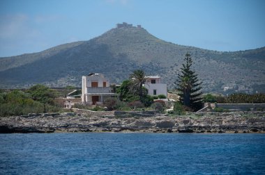 Trapani 'den tekne gezisi ve açık turkuvaz suyu, tuff kayaları, terk edilmiş taş ocakları, Sicilya, İtalya yakınlarındaki Egadi Adaları ile birlikte Favignana adasının kıyı şeridi manzarası.
