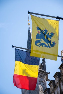 Belçika ulusal bayrağı ve Flanders 'ın sarı bayrağı Bruges, Belçika, mavi gökyüzünde rüzgarda dalgalanıyor