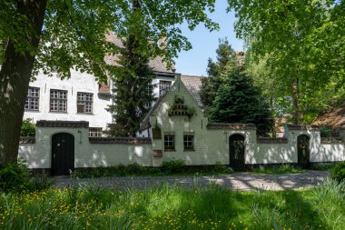 Bruges, Flanders 'da dantel ören rahibeler için ortaçağ manastırı, küçük beyaz evler ve Belçika' nın manastır duvarları içinde bir park.