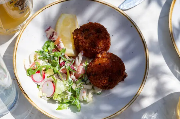 Açık kafede öğle yemeği. Vejetaryen peyniri ve yeşil kuşkonmaz kroket yanında taze salata ve Belçika, Bruges 'de patates kızartması.