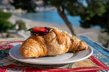 Mondello sahilinde İtalyan kahvaltısı, ricotta peyniri ve reçelle doldurulmuş taze tereyağlı kruvasan, Palermo, Sicilya 'da güneşli bir günde servis edilen açık hava,