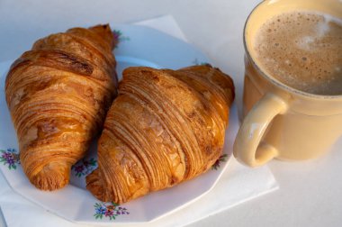 Taze pişmiş iki tereyağlı kruvasan ve bir fincan kahveyle servis edilen Avrupa kahvaltısı veya Fransız kahvaltısı.