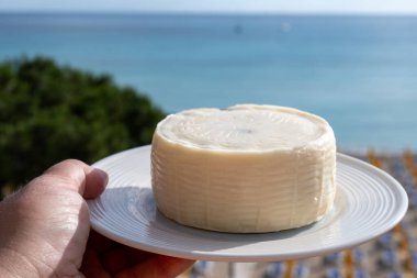 Primo İndirimli Sert Peynir. Karışık sütten yapılmış. Sicilya sepetinin ince kabuğu ve deseni turşulu kapari ve Sicilya, Mondello sahilinde deniz manzaralı.